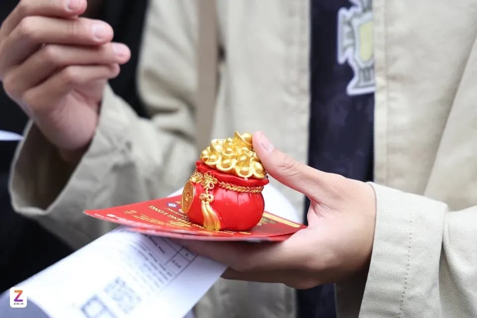 Một người cầm túi vàng nhỏ có tượng Thần Tài, tượng trưng cho việc đón Thần Tài một cách tỉnh thức và giá trị tâm linh.