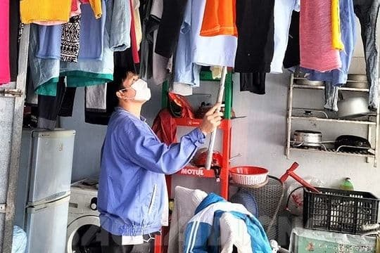 Một người lao động đang phơi quần áo trong không gian sống của mình, thể hiện lựa chọn nghỉ lễ tại nhà hoặc tận hưởng thời gian riêng tư.