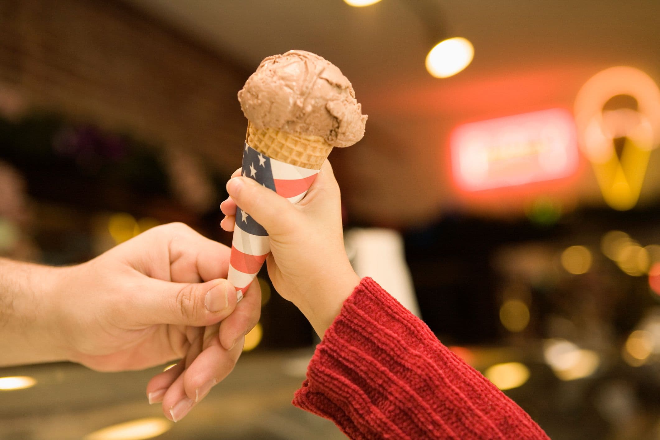 Một người đàn ông đang đưa kem cho một bé gái, tượng trưng cho việc giải nhiệt trong thời tiết nóng.