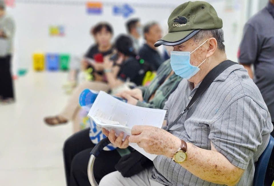Một người đàn ông cao tuổi đeo khẩu trang đang đọc tài liệu, có thể liên quan đến thông tin lương hưu hoặc chính sách mới.