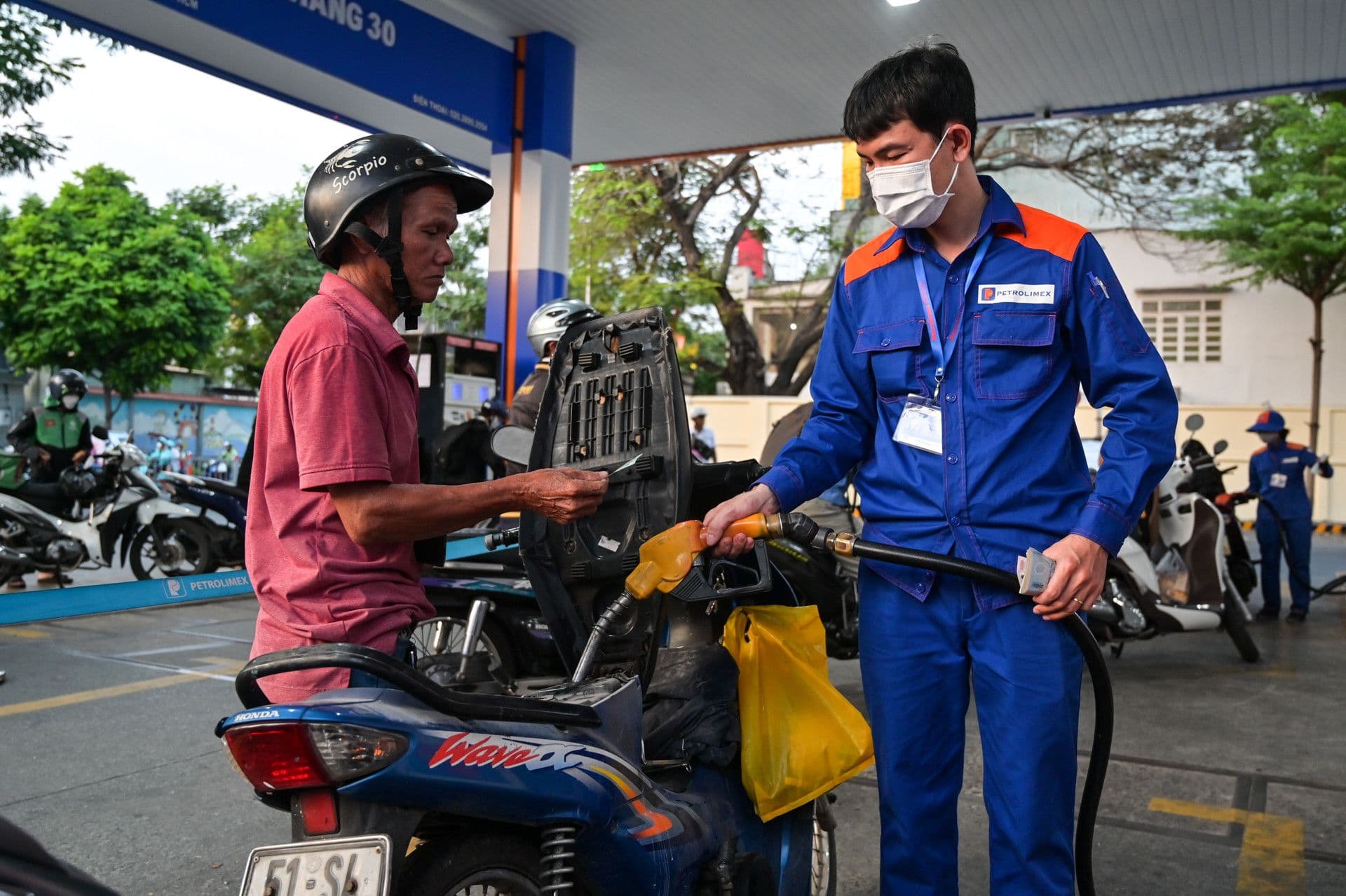 Một người đàn ông đổ xăng vào xe máy tại trạm Petrolimex, thể hiện sự tương tác trực tiếp của người dân với giá xăng dầu.
