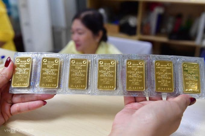 Một người phụ nữ đang cầm một vỉ gồm nhiều miếng vàng SJC, thể hiện hoạt động giao dịch vàng miếng tại thị trường Việt Nam.