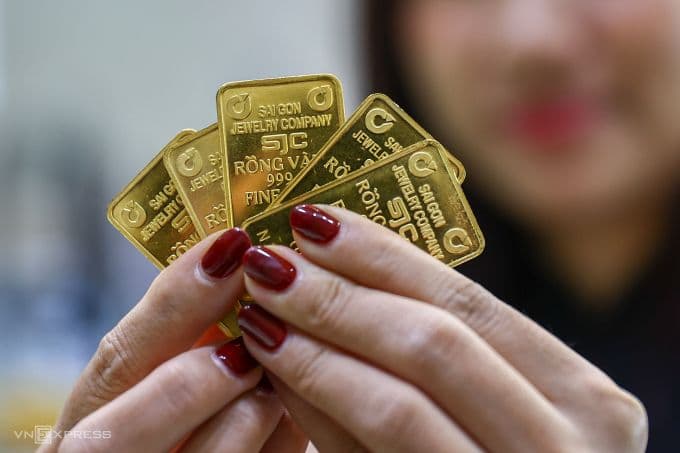 Một người phụ nữ đang cầm nhiều miếng vàng SJC, minh họa cho thị trường vàng trong nước và những thách thức cho nhà đầu tư.