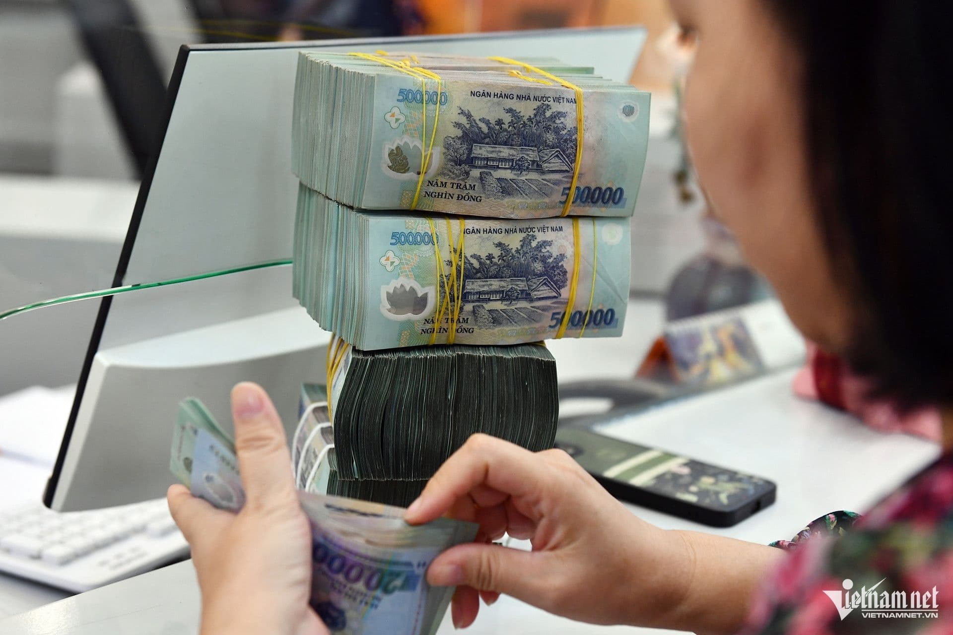 Một người phụ nữ đang đếm những cọc tiền mệnh giá lớn, tượng trưng cho khái niệm tiền bạc và sự giàu có.