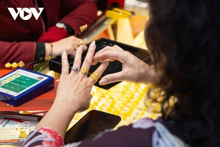 Một người phụ nữ đang thử nhẫn vàng tại quầy giao dịch, minh họa hoạt động mua bán vàng trong cơn sốt giá.