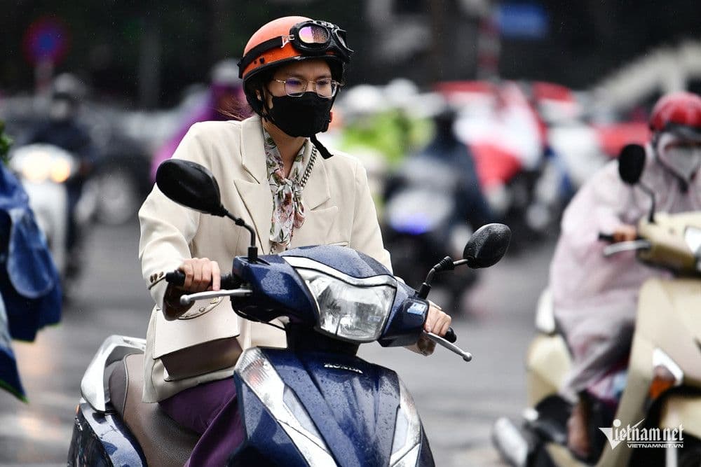 Một người phụ nữ đi xe máy trong mưa ở Sài Gòn, minh họa cuộc sống hàng ngày chịu ảnh hưởng của thời tiết.