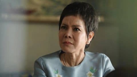 Một người phụ nữ lớn tuổi với vẻ mặt nghiêm nghị, thể hiện sự lo lắng và căng thẳng trong một mối quan hệ gia đình phức tạp.