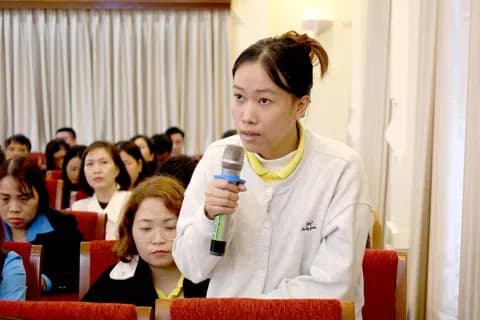 Một người phụ nữ phát biểu, tượng trưng cho việc chia sẻ lời khuyên và định hướng.