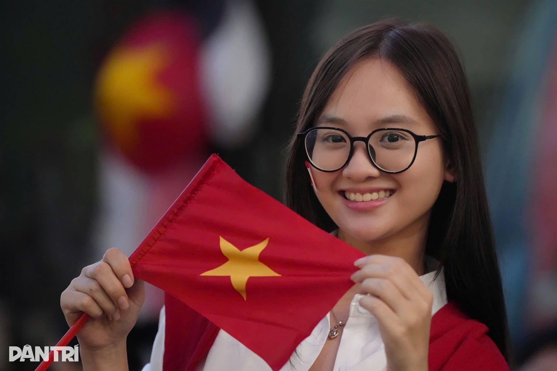 Một người phụ nữ trẻ mỉm cười tự hào, cầm lá cờ Việt Nam, thể hiện tình yêu nước trong ngày Quốc khánh.