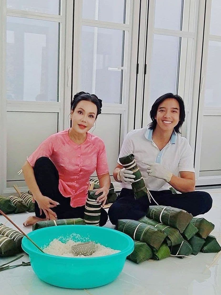 Một người phụ nữ và một thanh niên đang cùng nhau gói bánh chưng, thể hiện sự tiếp nối và gìn giữ truyền thống qua các thế hệ.