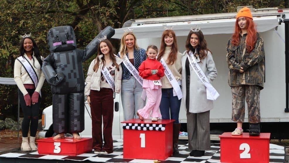 Một nhóm người, bao gồm một người trong trang phục linh vật và những người đoạt giải, đứng trên bục tại một sự kiện ngoài trời.