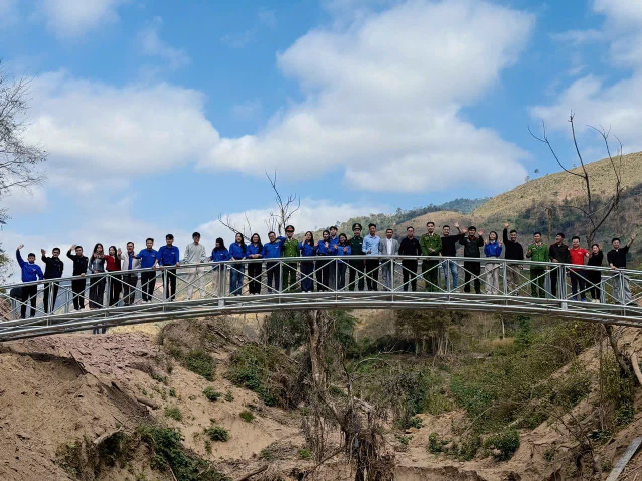 Một nhóm người trên cây cầu mới xây, thể hiện sự gắn kết và đóng góp cho cộng đồng.