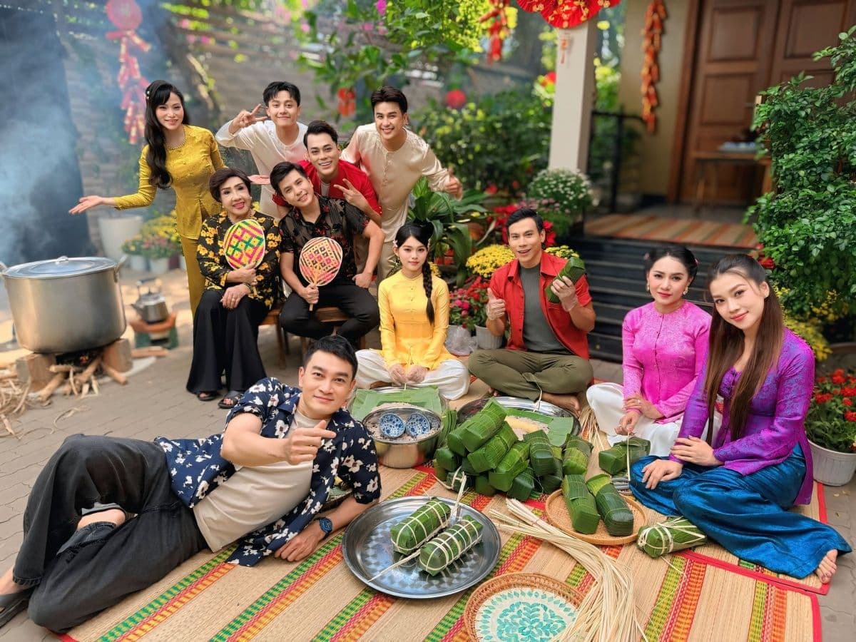 Một nhóm người Việt mặc trang phục truyền thống quây quần gói bánh chưng và luộc bánh trong không khí Tết sum vầy.