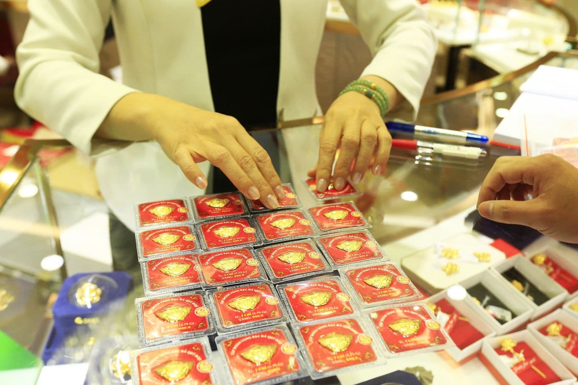 Một nhân viên đang sắp xếp hoặc giao dịch vàng miếng SJC tại quầy, thể hiện hoạt động thị trường vàng sôi động của Việt Nam.
