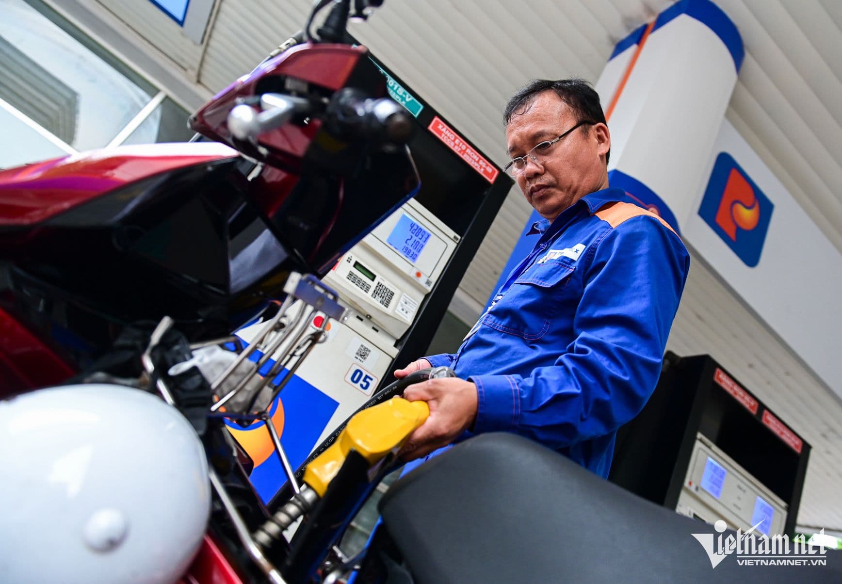 Một nhân viên đang đổ xăng cho xe máy, tượng trưng cho hoạt động điều tiết giá xăng dầu thông qua tạm ứng ngân sách.