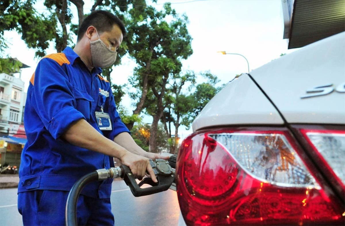 Một nhân viên đang đổ xăng vào ô tô tại trạm xăng, minh họa cho việc tiêu thụ dầu và giá xăng dầu.