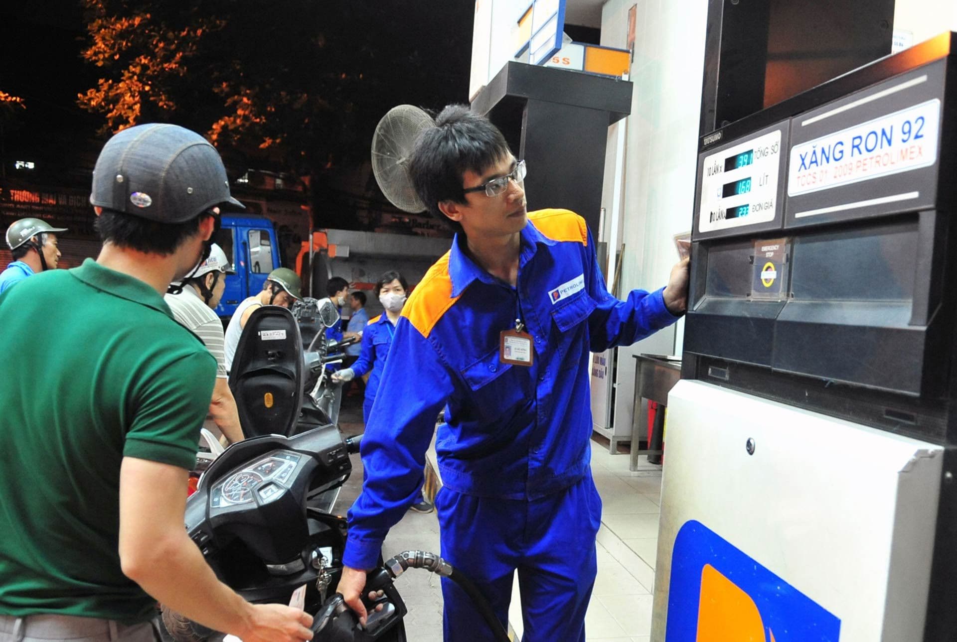 Một nhân viên cây xăng đang điều chỉnh trụ bơm xăng RON 92 cho khách hàng, thể hiện sự biến động giá xăng dầu.