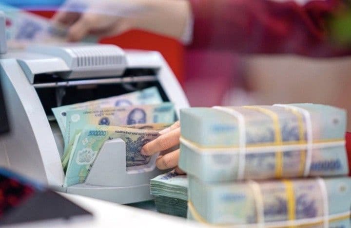 Một nhân viên ngân hàng đang đếm tiền Việt Nam bằng máy, tượng trưng cho hoạt động tiền gửi và dòng vốn trong ngân hàng.