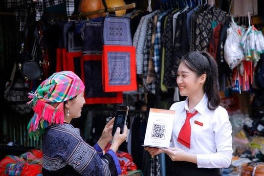 Một nhân viên ngân hàng hướng dẫn khách hàng sử dụng dịch vụ tài chính số, thể hiện sự tiện lợi và phổ cập.