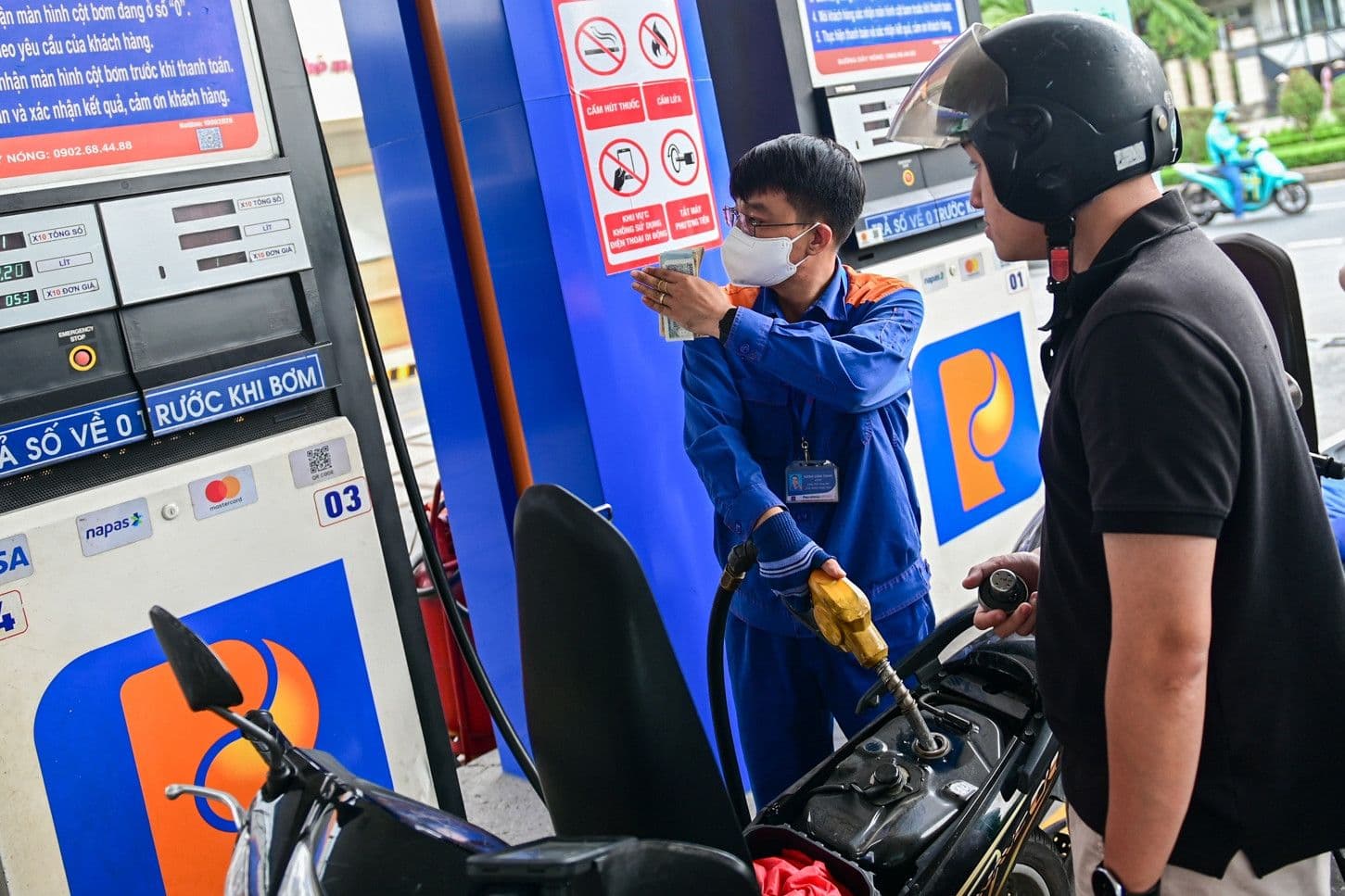 Một nhân viên Petrolimex đang đổ xăng cho xe máy của khách hàng, minh họa tác động trực tiếp của giá xăng dầu lên chi tiêu và đời sống hàng ngày của người dân.