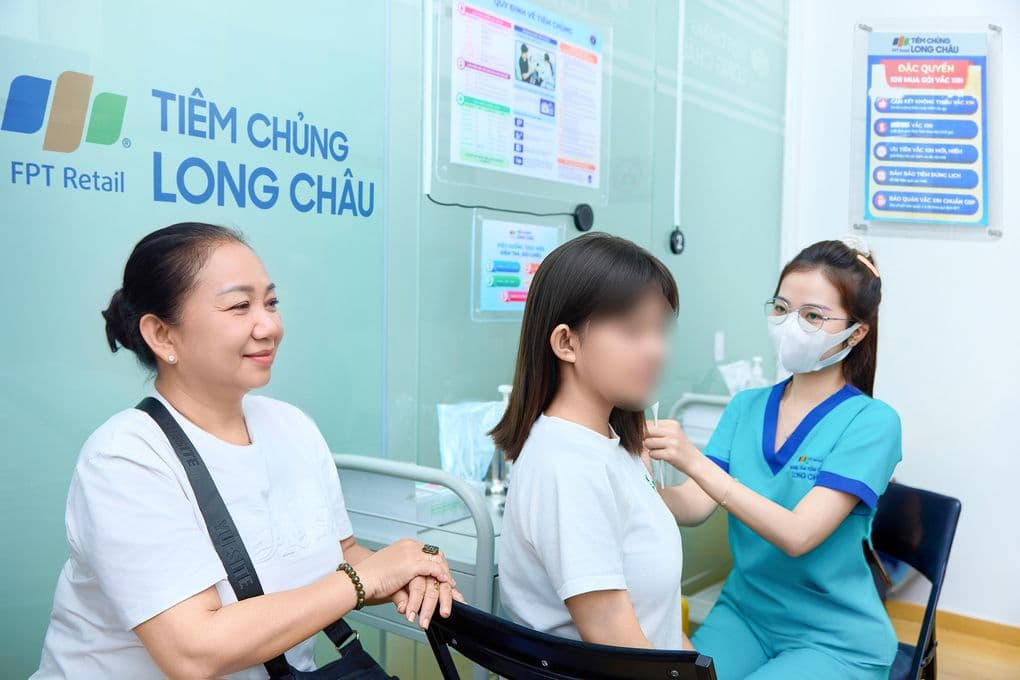 Một phụ nữ trẻ đang được tiêm vắc xin HPV tại phòng khám, bên cạnh là người thân, thể hiện tầm quan trọng của việc phòng ngừa ung thư cổ tử cung.
