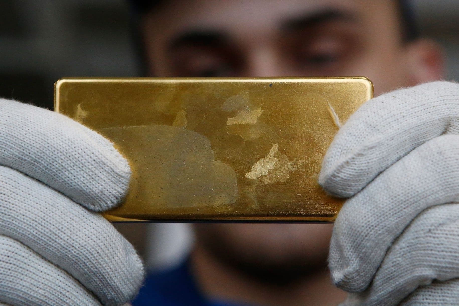 Một thỏi vàng được kiểm tra, biểu tượng của tài sản bị ảnh hưởng bởi các chính sách tiền tệ và diễn biến địa chính trị toàn cầu.