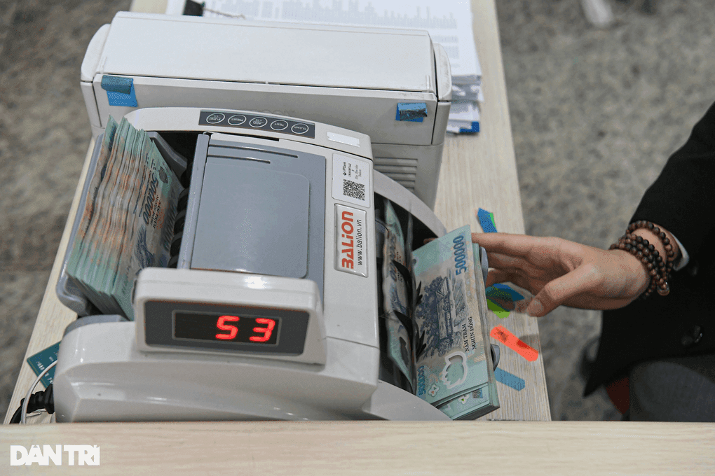 Máy đếm tiền với các tờ 500.000 VNĐ, tượng trưng cho hoạt động gửi tiền và lãi suất ngân hàng