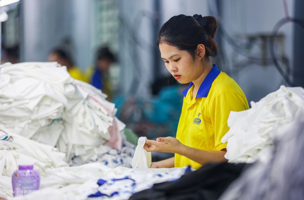 Nữ công nhân dệt may đang làm việc trong nhà máy, thể hiện năng suất lao động và hoạt động sản xuất của doanh nghiệp.