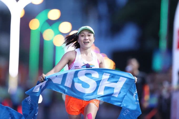 Nữ vận động viên vui mừng cán đích với banner 'FINISH', thể hiện niềm vui chiến thắng và tinh thần hoàn thành cuộc đua tại Nha Trang.