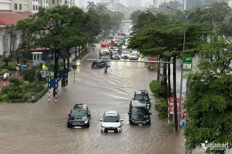Đường phố Hà Nội ngập lụt nặng nề do ảnh hưởng của bão, xe cộ di chuyển khó khăn trong dòng nước.
