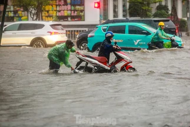 Đường phố Hà Nội ngập sâu, người dân chật vật di chuyển sau mưa lớn, cảnh báo lũ lụt.