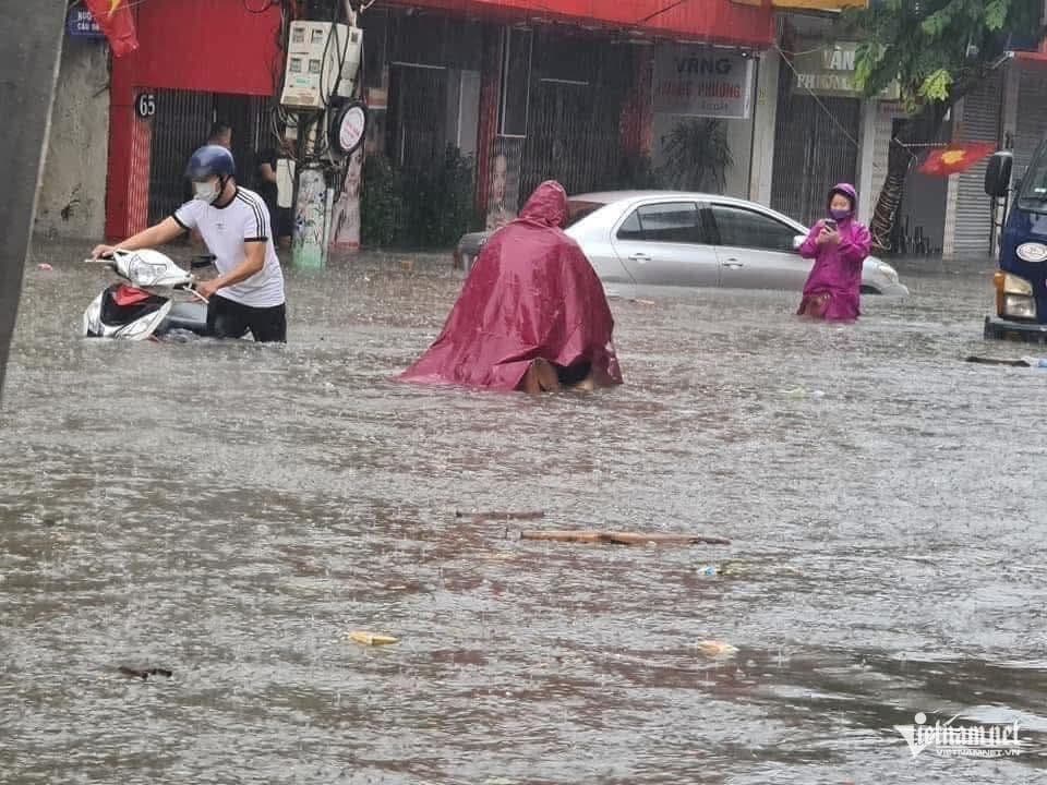 Đường phố ngập lụt với người dân lội nước, thể hiện tác động của thời tiết cực đoan và nỗi lo về biến đổi khí hậu.