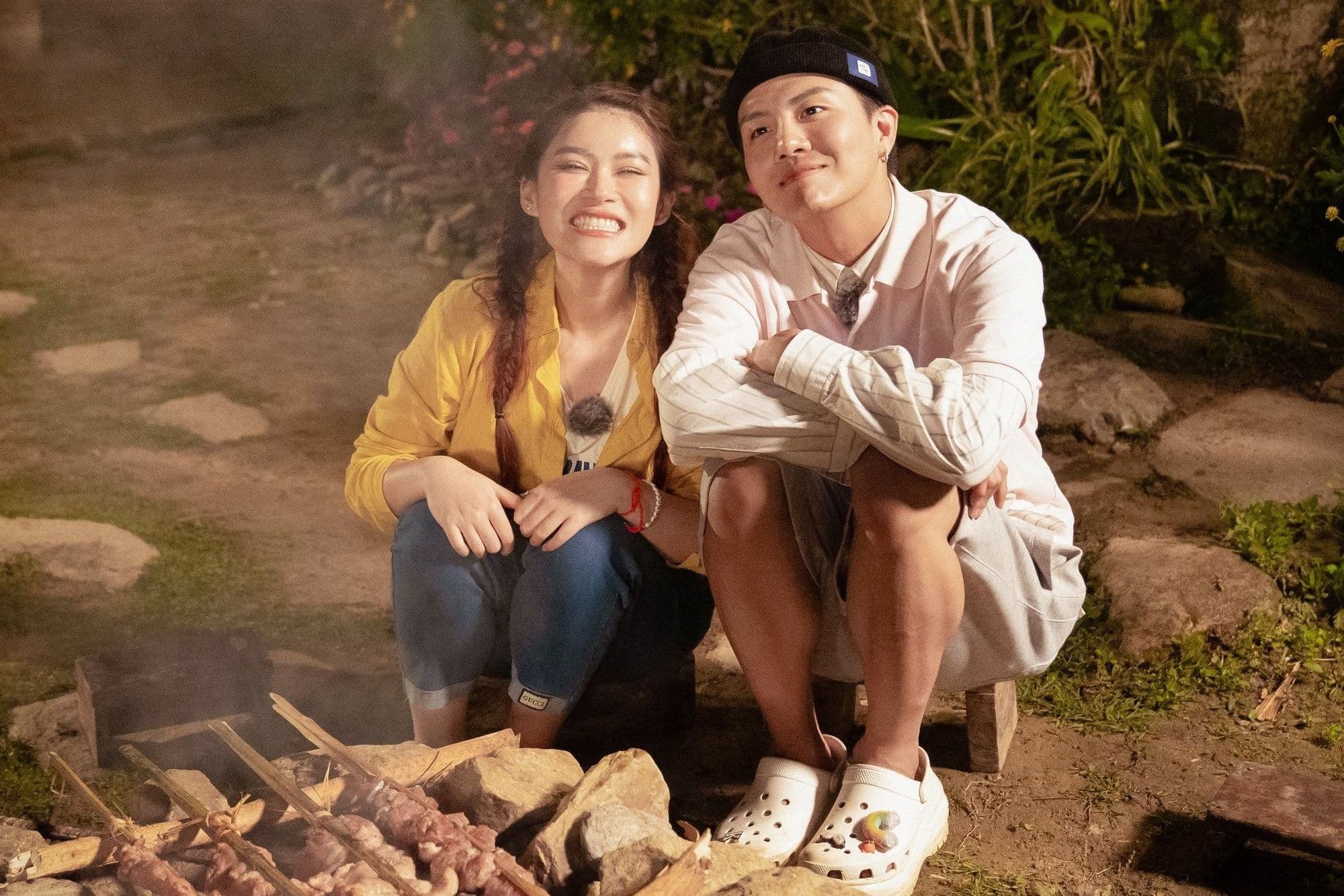 Ngọc Thanh Tâm và một thành viên trong chương trình thực tế Gia Đình Haha đang nướng thịt bên lửa trại, thể hiện sự gần gũi và chân thực.