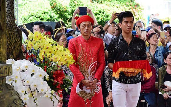 Nghệ sĩ Hoài Linh trong trang phục truyền thống màu đỏ, tham gia nghi lễ tâm linh, tượng trưng cho sự tái tạo và tìm kiếm giá trị tinh thần.