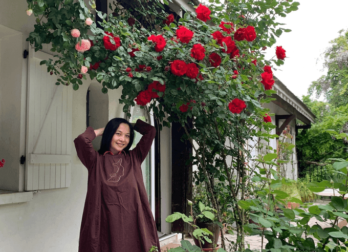 Nghệ sĩ Lê Vi mỉm cười trong khu vườn đầy hoa hồng tại nhà riêng ở Pháp.