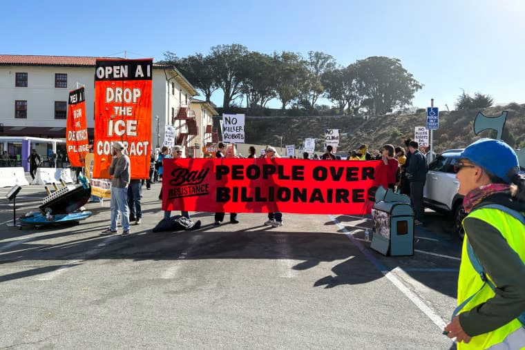Người biểu tình cầm biểu ngữ 'People over billionaires' và các khẩu hiệu chống AI, thể hiện sự lo ngại về công nghệ.