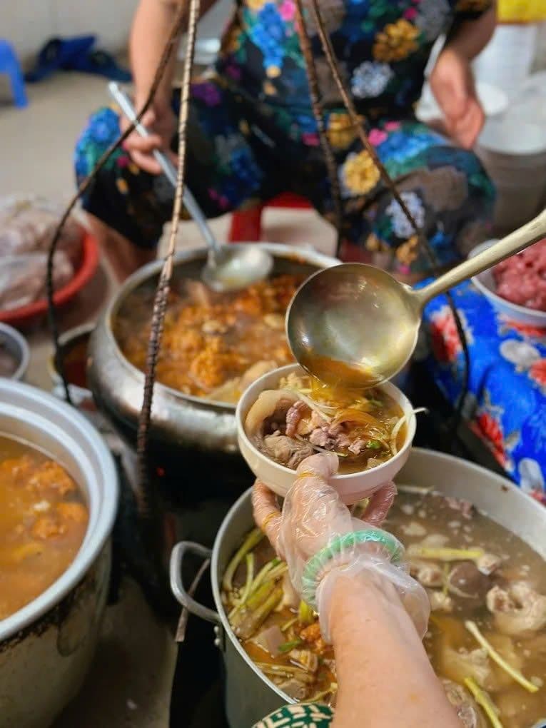 Người bán đang múc bún bò Huế từ nồi lớn vào tô, thể hiện sự chuẩn bị truyền thống.