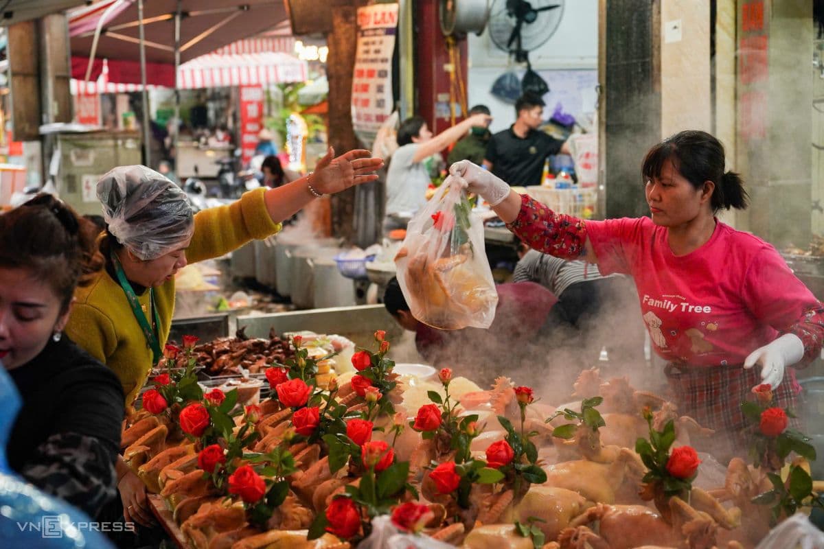 Người bán hàng đang sắp xếp những con gà luộc trang trọng tại chợ, chuẩn bị cho các gia đình sắm lễ cúng, tượng trưng cho sự khởi đầu mới và may mắn.