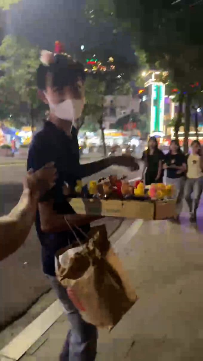 Người bán hàng rong đeo bờm tai mèo và khẩu trang, cầm khay đồ chơi, bị tố quấy rối du khách tại Hồ Gươm.