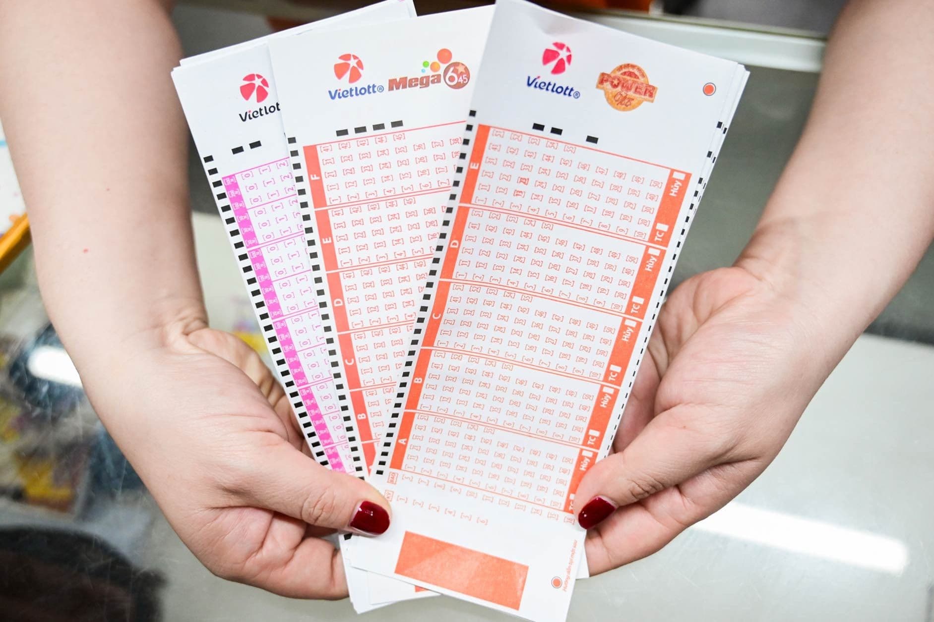 Người chơi cầm trên tay các vé số Vietlott Mega 6/45 và Power 6/55, thể hiện sự kỳ vọng vào cơ hội trúng thưởng lớn.