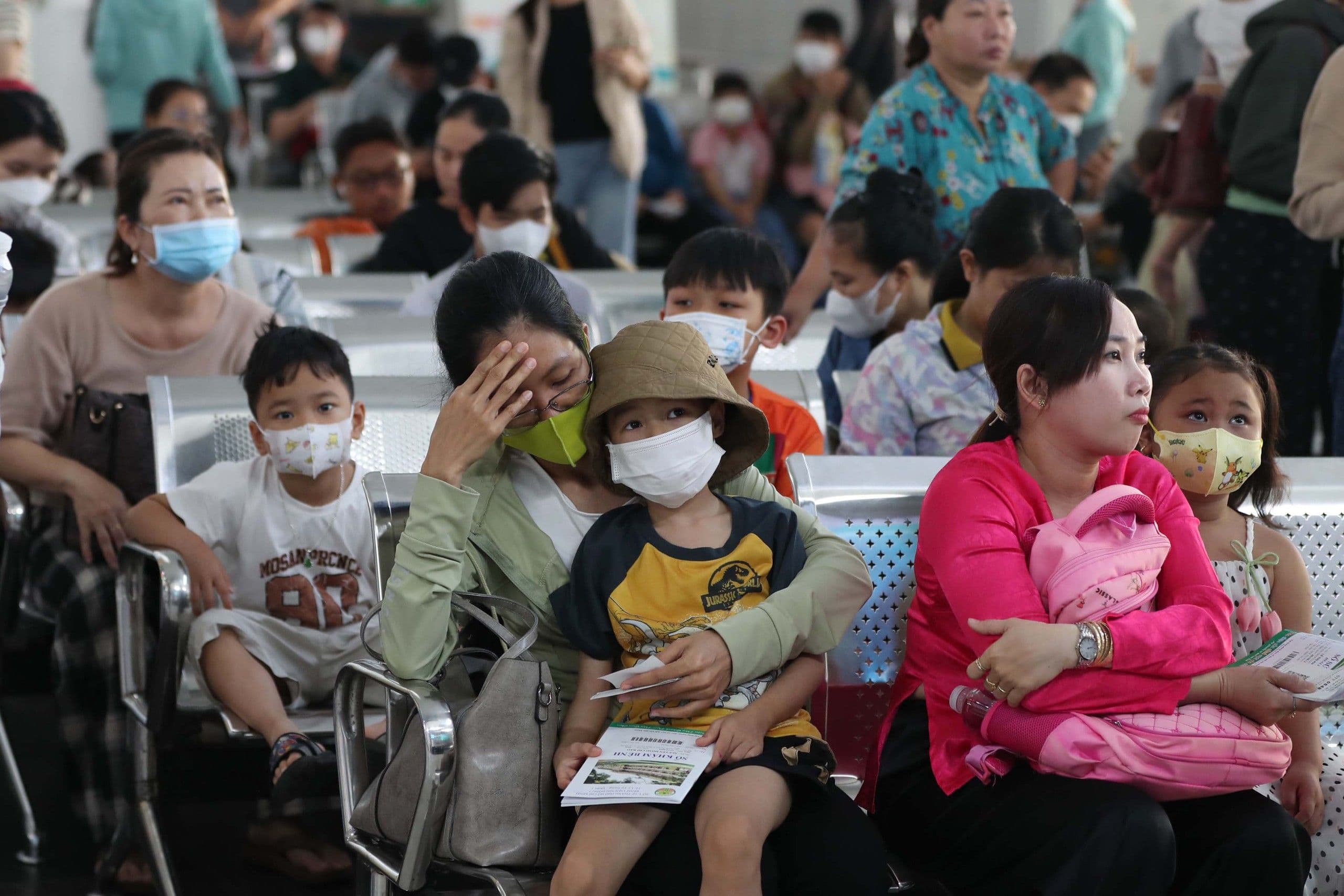 Người dân, đặc biệt là trẻ nhỏ, đeo khẩu trang chờ khám tại bệnh viện trong mùa dịch hô hấp.