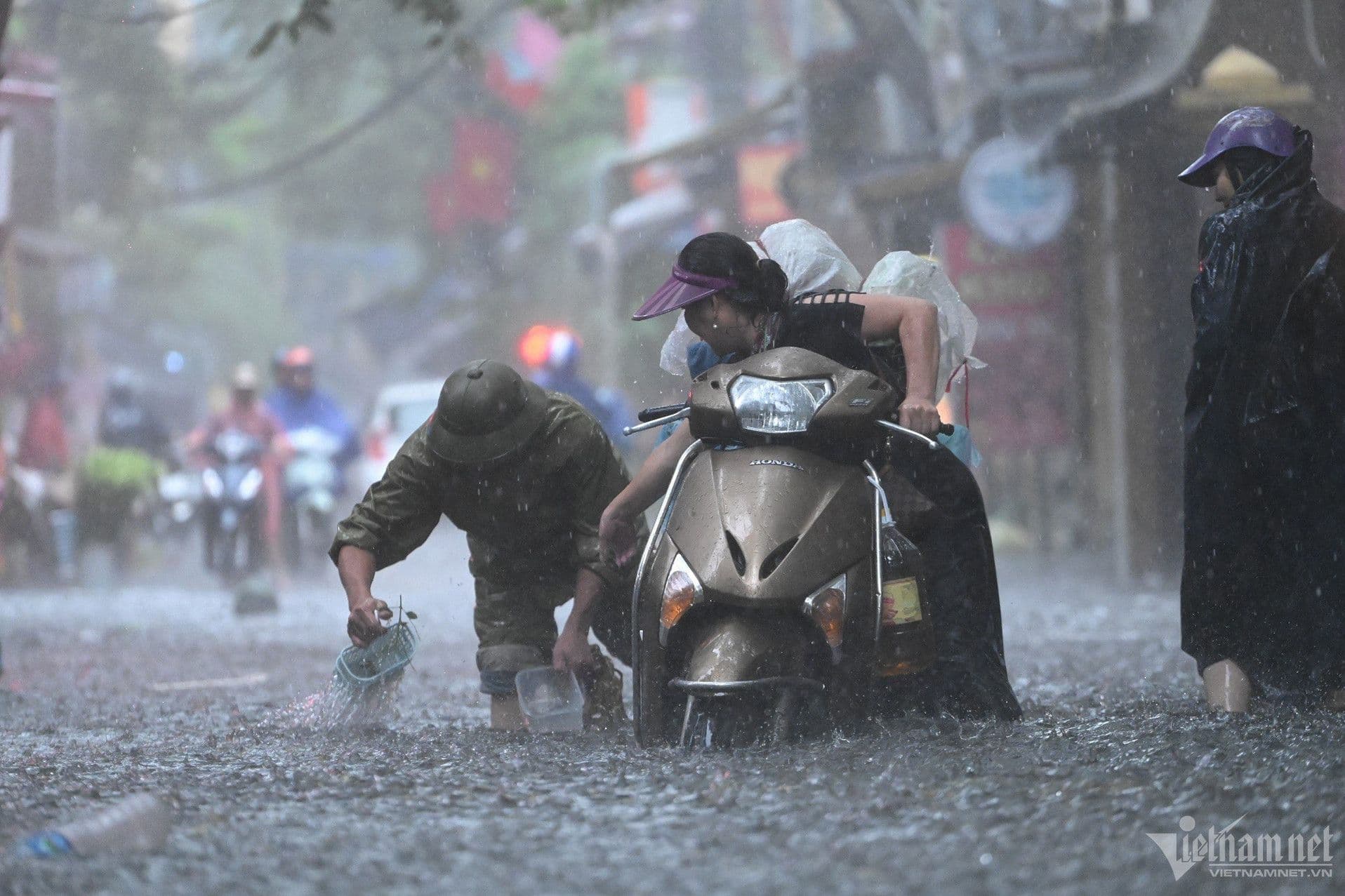 Người dân cố gắng di chuyển xe máy qua đường ngập lụt, minh họa sự thích nghi tức thì với mưa lớn.