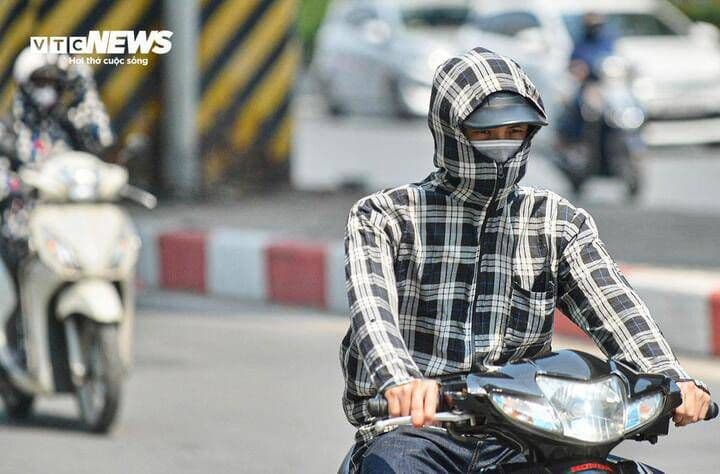 Người dân che chắn kỹ lưỡng khi di chuyển dưới trời nắng nóng gay gắt tại miền nhiệt đới.