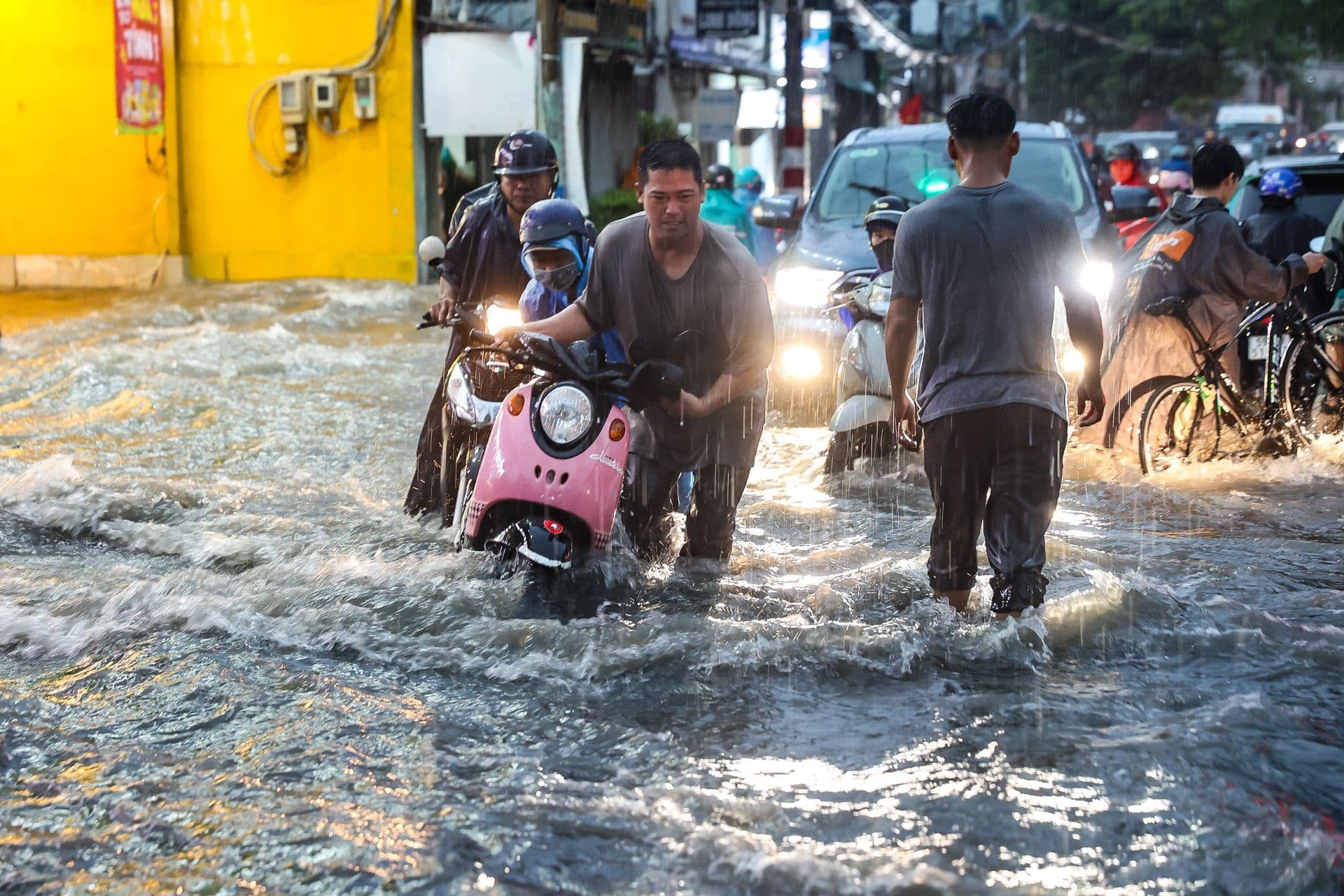 Người dân chật vật di chuyển qua đường phố TP.HCM ngập sâu do mưa lớn