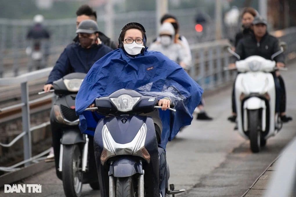 Người dân di chuyển bằng xe máy trong thời tiết rét kèm mưa ở miền Bắc