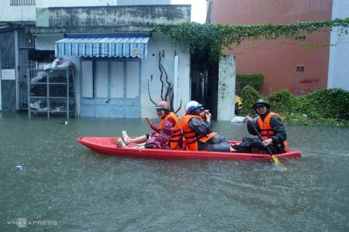 Người dân di chuyển bằng xuồng trên đường phố ngập lụt do ảnh hưởng của bão số 12.