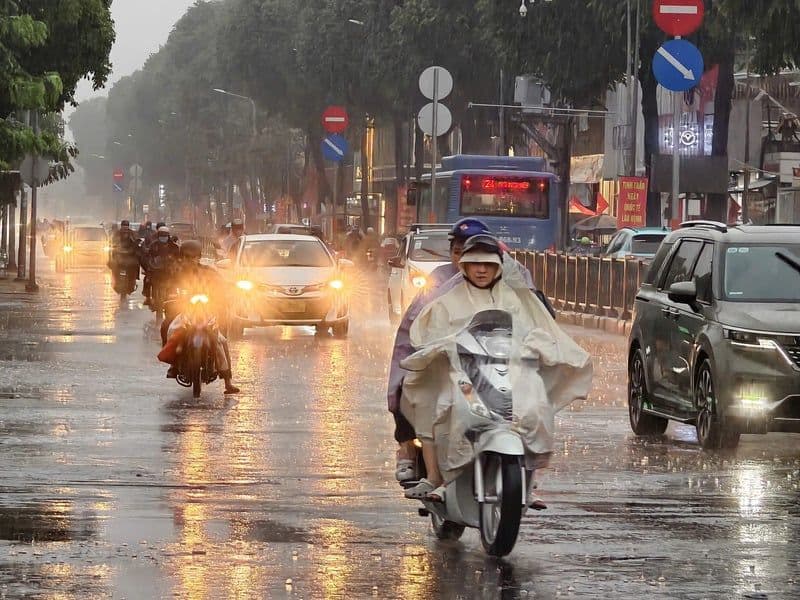 Người dân di chuyển dưới mưa lớn trên đường phố Việt Nam, minh họa khí hậu nhiệt đới ẩm gió mùa đặc trưng