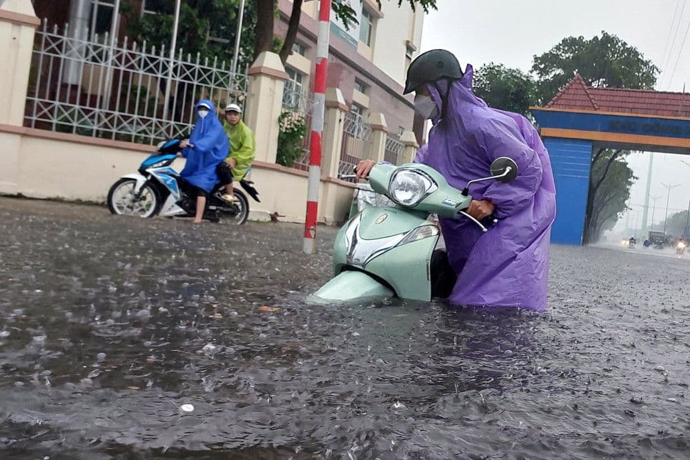 Người dân di chuyển khó khăn trên đường ngập lụt do mưa lớn ở Đà Nẵng, thể hiện sự đối phó của con người với thời tiết khắc nghiệt.