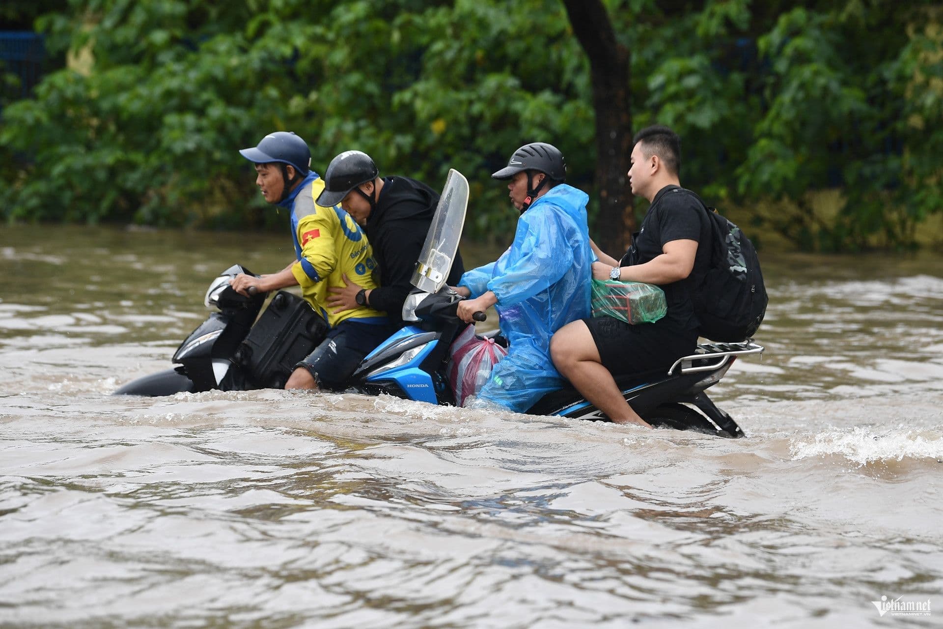 Người dân di chuyển khó khăn trên đường phố ngập sâu sau bão, minh họa hậu quả nặng nề của thiên tai