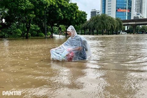Người dân di chuyển khó khăn trên tuyến đường ngập sâu ở Hà Nội do mưa lớn.